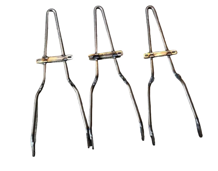 Three raw steel sissy bars with mounting tabs, arranged side by side on a concrete surface.